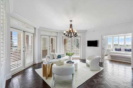 Staged living room with white seating, plantation shutters, a chandelier, and dark herringbone flooring.