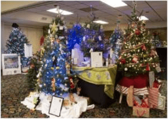 Holiday tree festival display with decorated Christmas trees, colorful lights, and wrapped gifts.