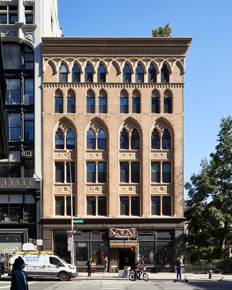 Historic tan brick building at 808 Broadway with ornate Gothic windows and street-level storefronts.