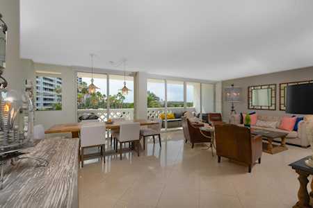 Open-plan condo living and dining room with large windows, polished tile floors, and a granite counter.