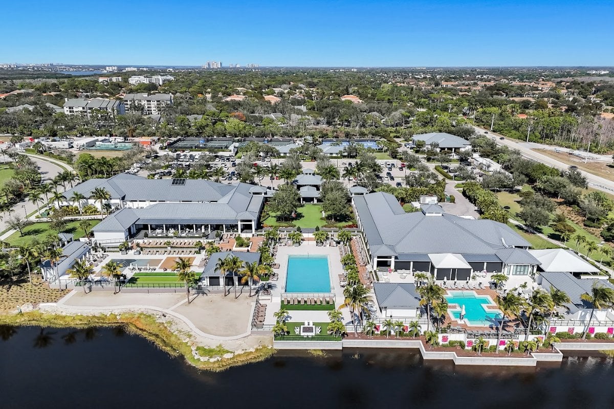 Aerial view of The Club at Kalea Bay: the clubhouse buildings, lap pool, resort pool and event lawn on the far side of the community lake.
