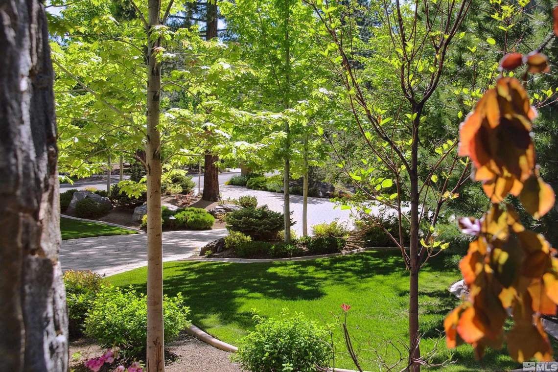 Landscaped grounds with a curved walkway, manicured lawn, shrubs, and mature trees.
