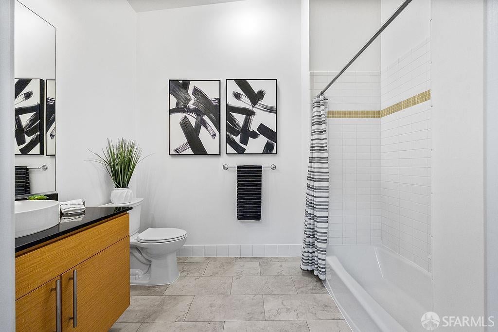 Bathroom with a wood vanity, tiled bathtub and striped shower curtain, and abstract wall art.