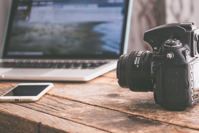 a-camera-cellphone-and-a-compter-on-a-wooden-table