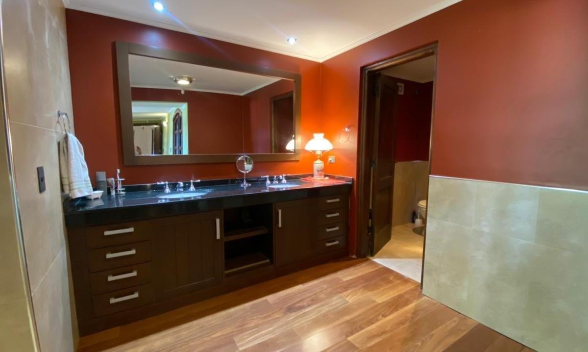 Bathroom with a long dark wood vanity, black countertop, large mirror, and warm red walls.