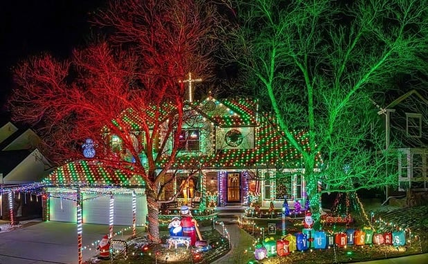 Festive Denver home covered in holiday lights with glowing trees, roofline lights, and yard decorations at night.