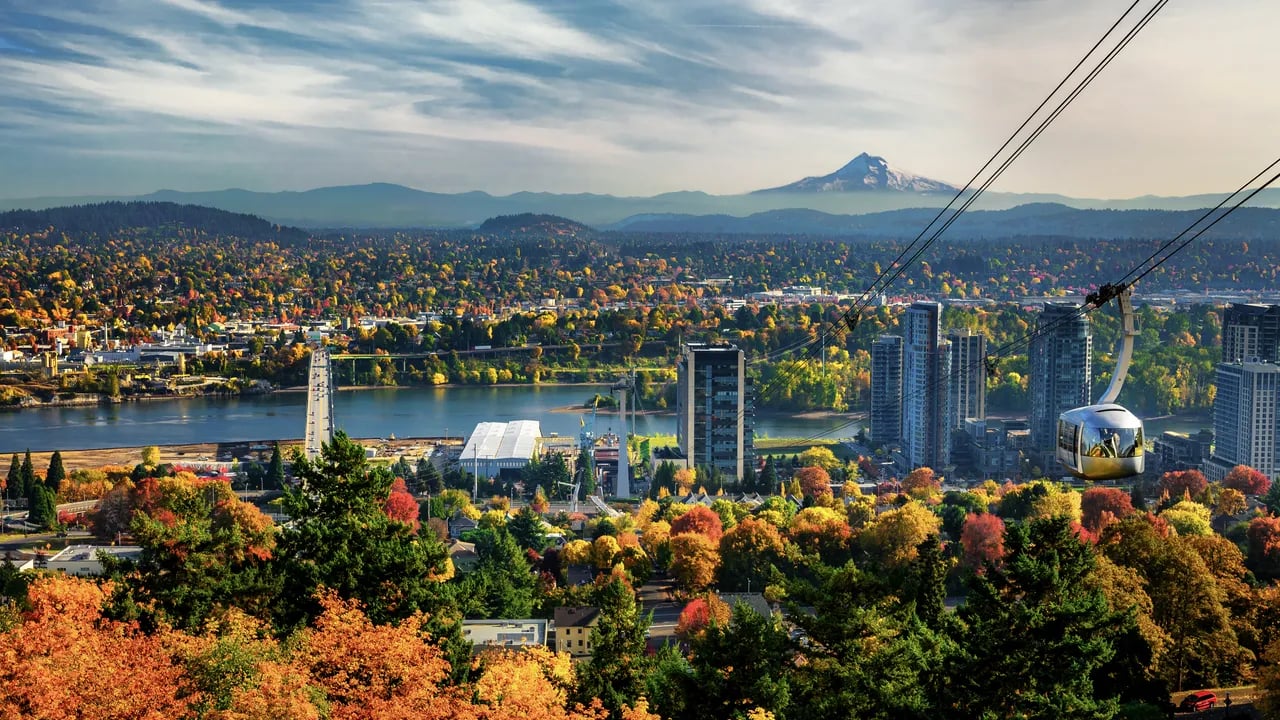 A panoramic fall view of Portland, Oregon, showcasing the city skyline, Portland Aerial Tram, and Mount Hood in the background—perfectly capturing why families and first-time buyers are choosing to move to Portland, OR