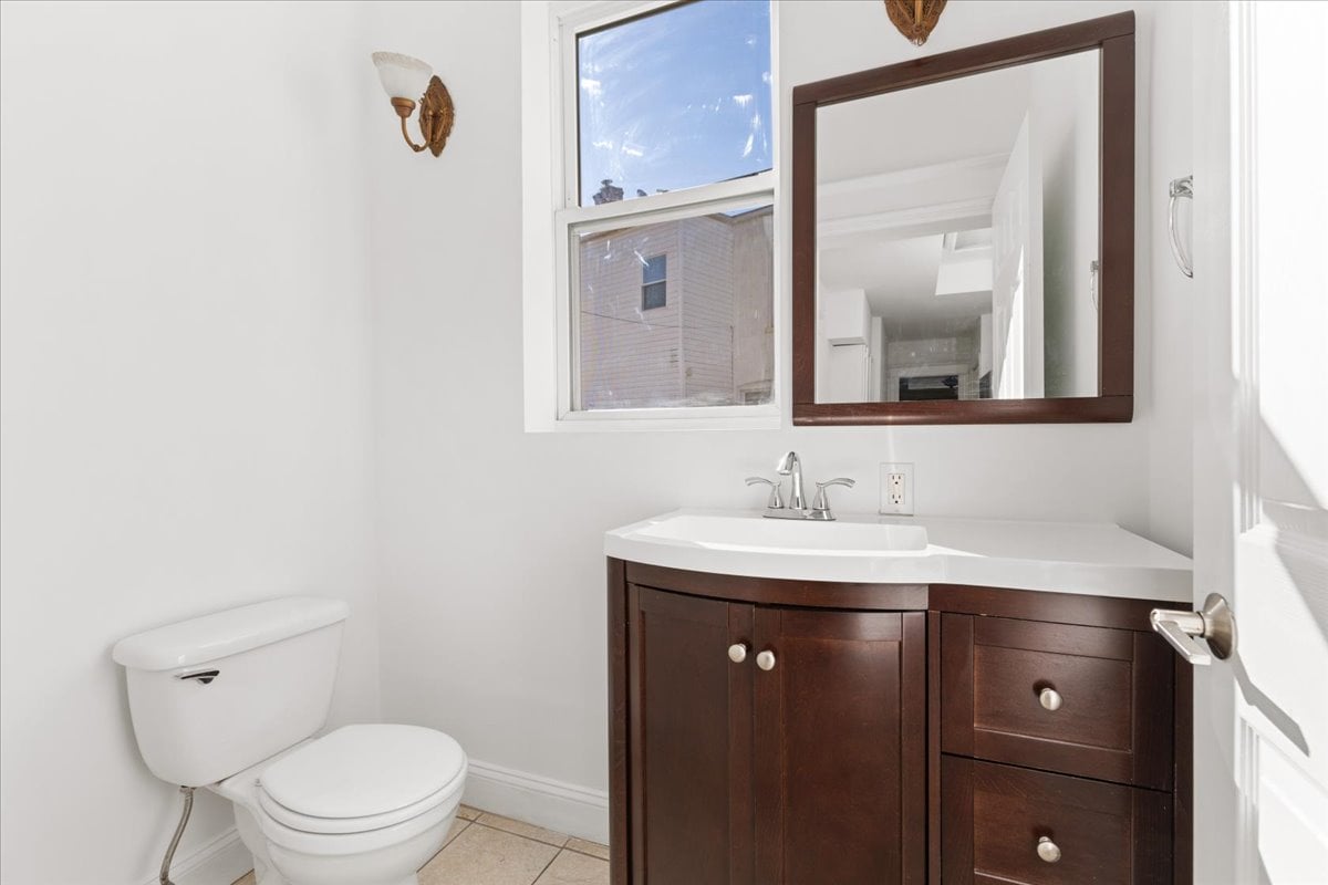 Bathroom with a dark wood vanity, framed mirror, and window above the sink.