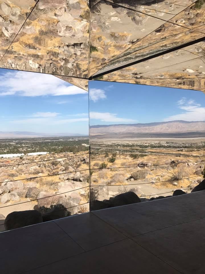 Mirrored Mirage installation reflects the desert valley, distant mountains, and rocky landscape.