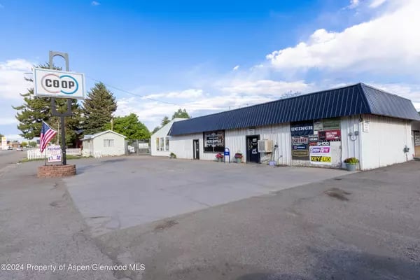 COOP store in Meeker with a roadside sign, American flag, and long white building.
