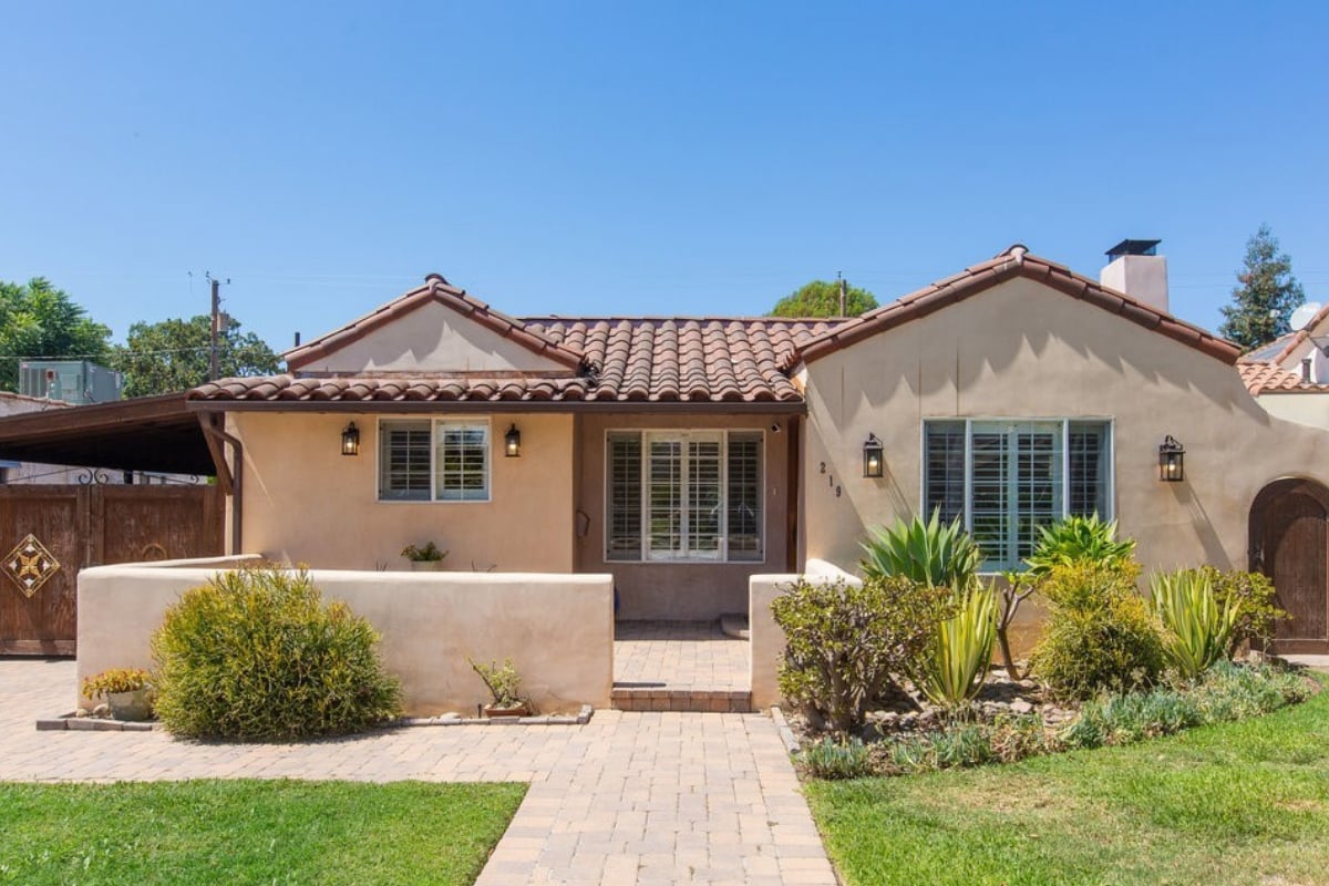 Single-story stucco home with a terracotta tile roof and landscaped front walkway.