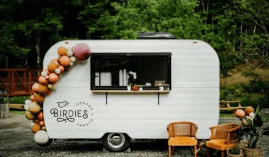 Birdies coffee trailer with an open service window, colorful balloon garland, and outdoor chairs.