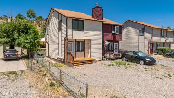 Attached homes with gravel parking, fenced yards, and a central red-sided unit.