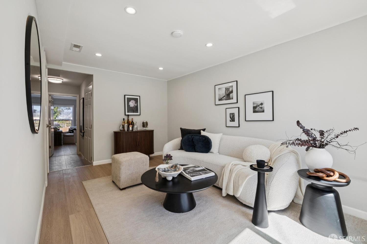 Staged living room with a curved white sofa and dark round coffee table.