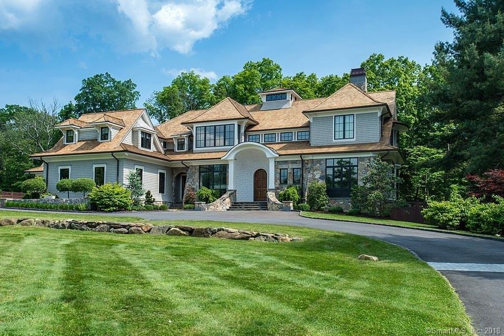 Large two-story home with stone accents, an arched entry, and a broad lawn.