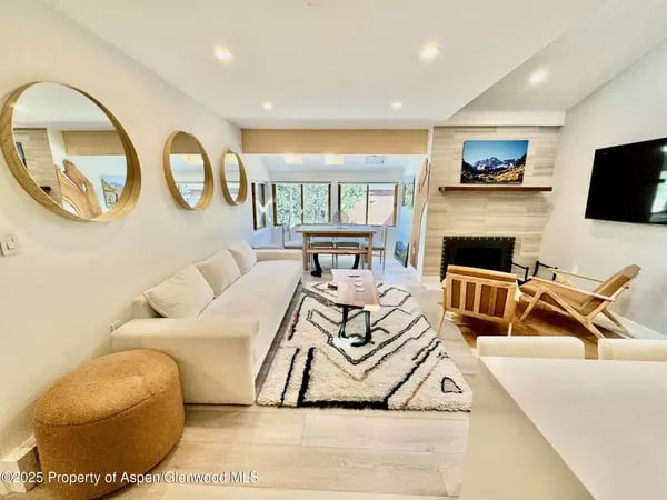 Bright living room with a white sofa, geometric rug, fireplace, and round mirrors.