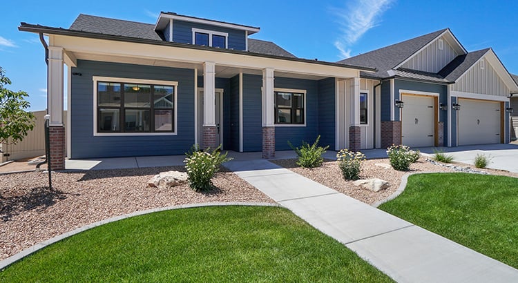 Blue-and-white home with a covered entry, two-car garage, and curved walkway through the front lawn.