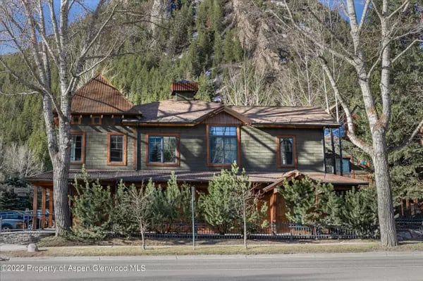 Wood-sided Aspen home with a broad deck, large windows, and wooded surroundings.