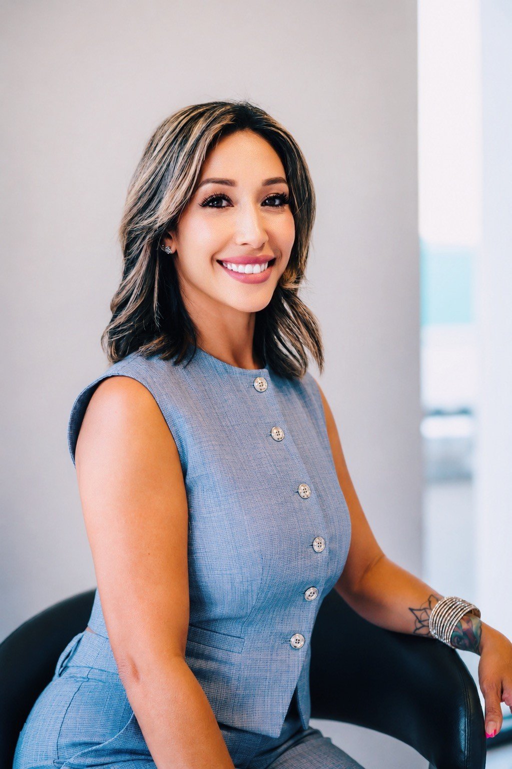 Brenda Lopez, a smiling real estate agent in a sleeveless blue outfit, seated for a portrait.