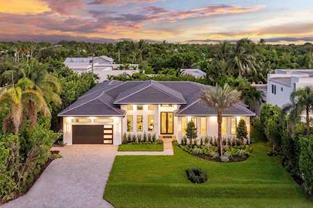 Modern single-story home with a wide driveway and landscaped lawn, viewed from above at dusk.