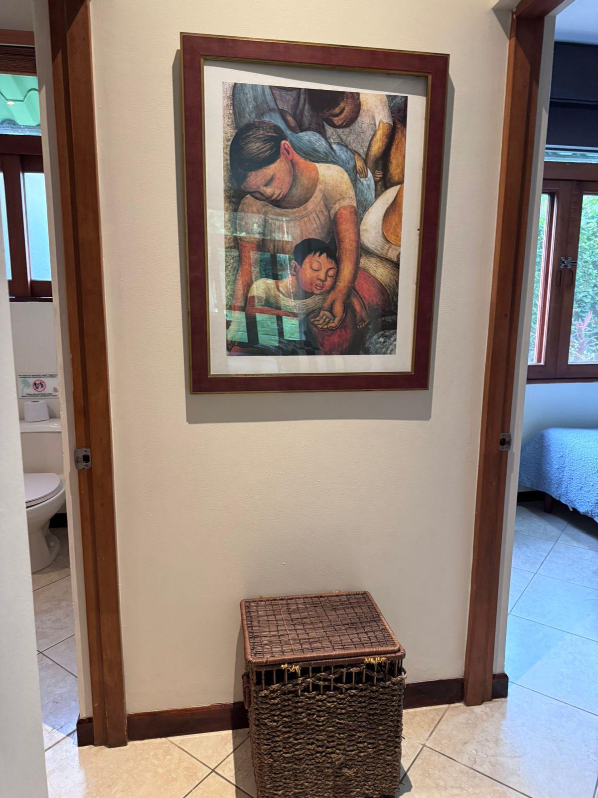 Condo hallway with framed artwork and a woven basket between bathroom and bedroom doorways.