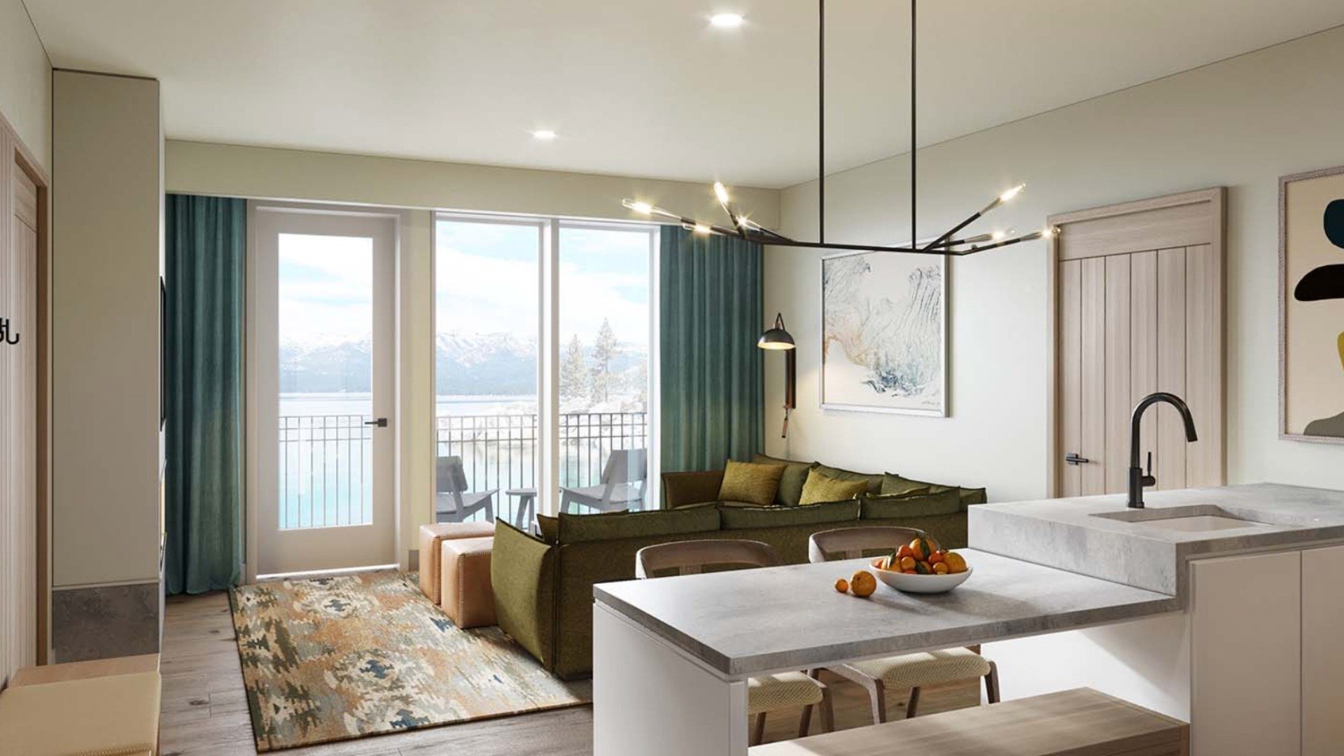 Open-plan living room and kitchen overlooking a lake and snow-covered mountains.