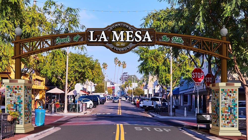 Downtown La Mesa Village entrance arch over a tree-lined street.