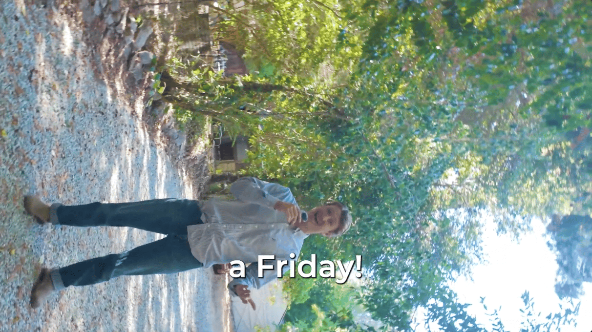 A man speaks into a microphone on a leafy path, with the caption “a Friday!”