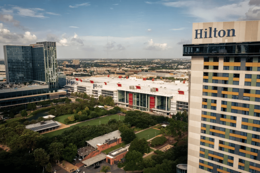 Convention center and landscaped grounds beside a Hilton hotel tower in Houston.