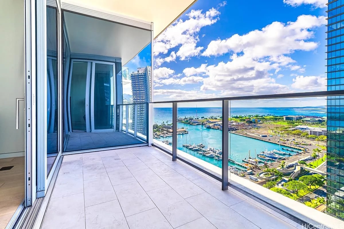 High-rise balcony overlooking a marina and ocean, with tiled flooring and glass railings.