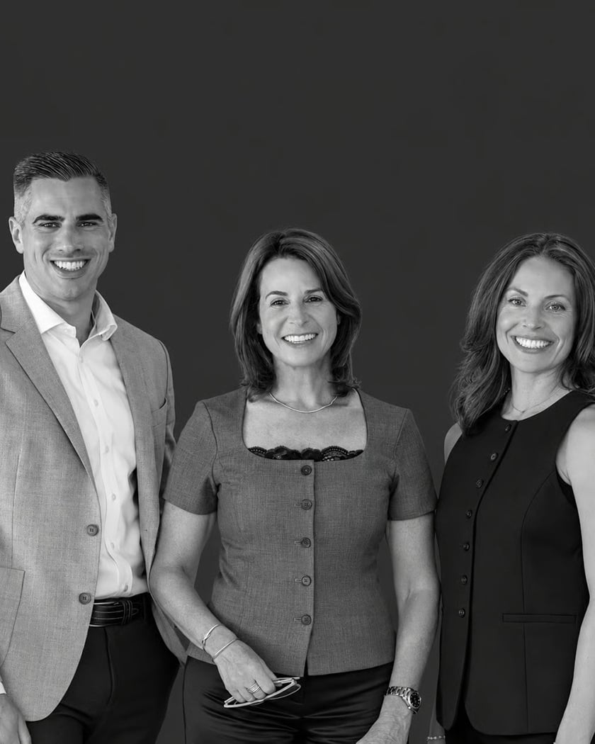 Three real estate agents pose together against a dark studio backdrop.