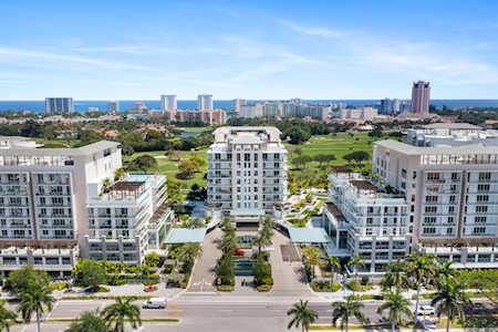 Aerial view of East Boca condominiums beside a golf course, with the city skyline in the distance.