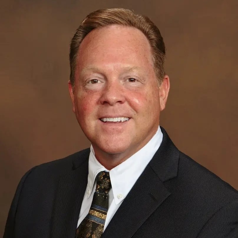 Robert McKenney, real estate agent, in a dark suit and patterned tie.