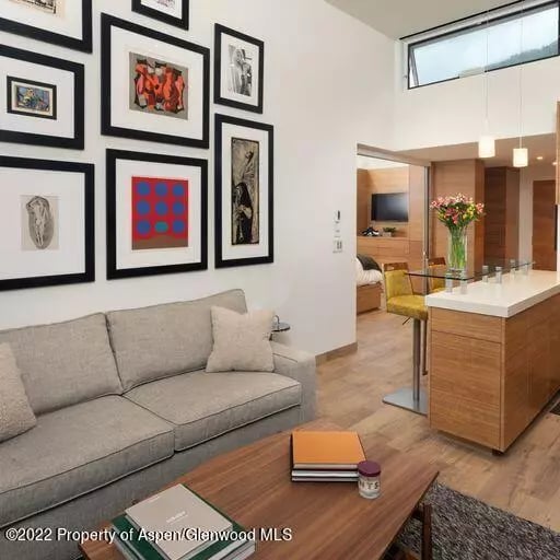 Modern living room with a gray sofa, framed art gallery wall, and wood kitchen island.
