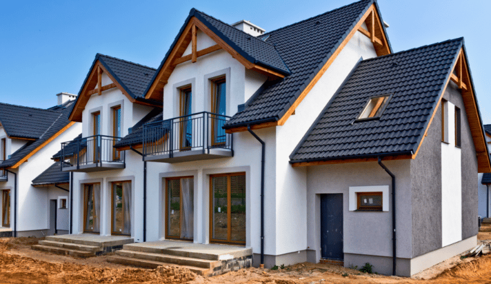 Newly built white house with dark tiled roofs, timber trim, and black balconies.