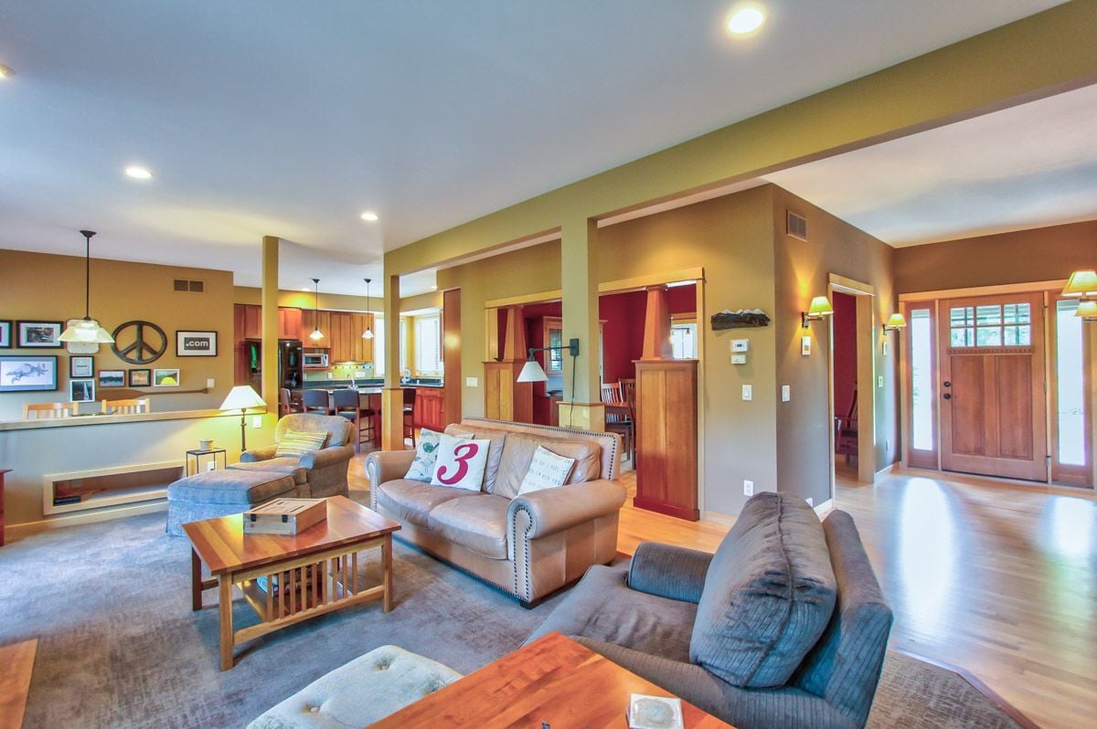 Open-plan living room with sofas, a wood coffee table, fireplace, and adjoining kitchen.