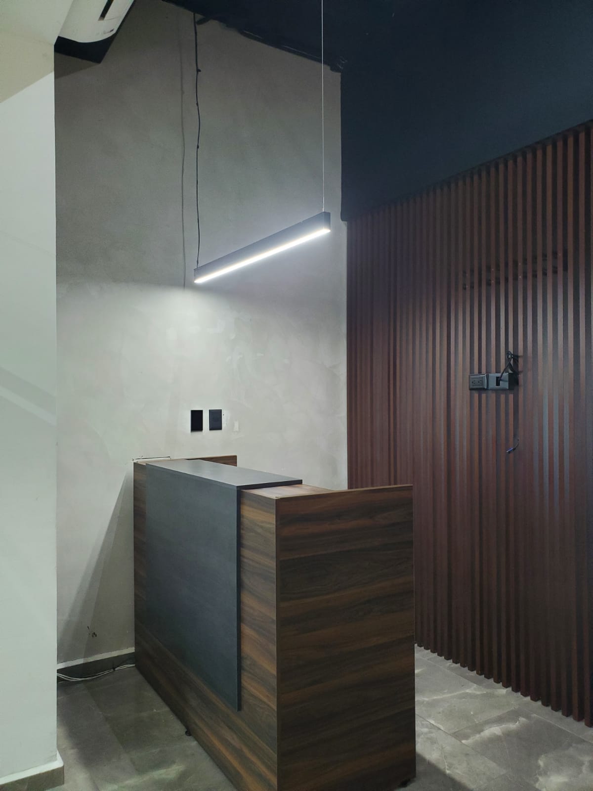 Office reception area with a wood-and-gray counter and vertical wood slat wall.