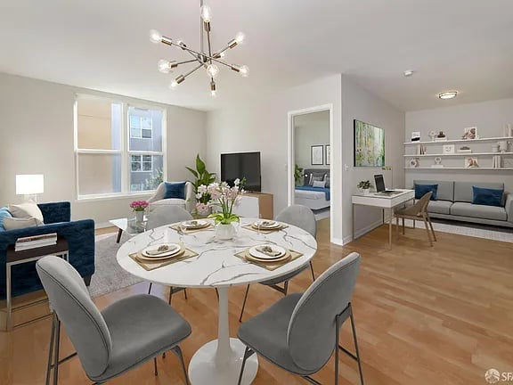 Staged open-plan living and dining area with a marble table, blue seating, and a built-in desk.