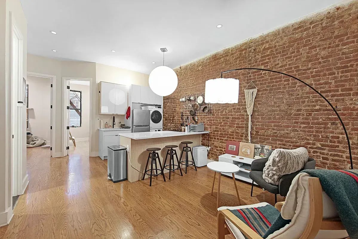 Open-plan kitchen and living area with an exposed brick wall and island seating.