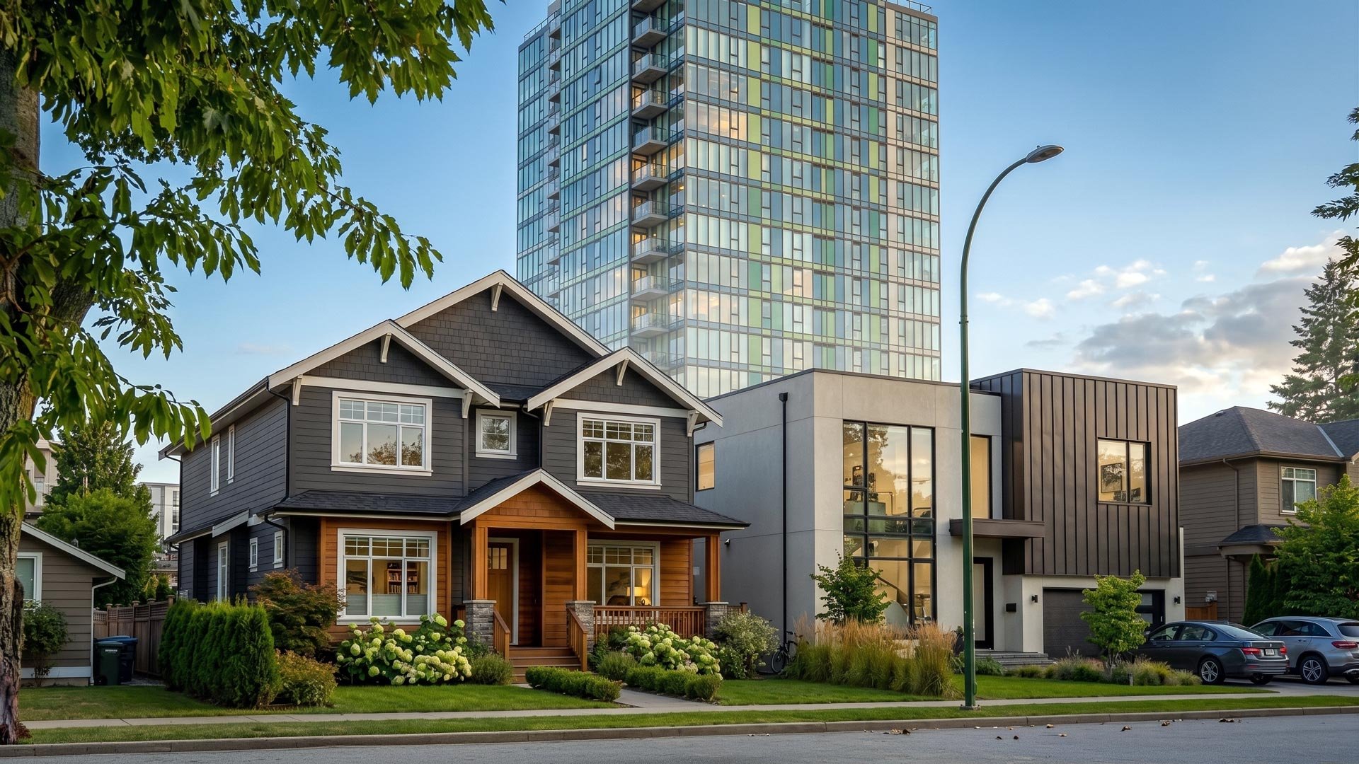 A side by side street view of a sleek modern custom house and a classic detached home positioned in front of a soaring luxury condominium tower in the background, illustrating the lifestyle comparison between a condo vs detached home GTA buyers consider when transitioning properties.