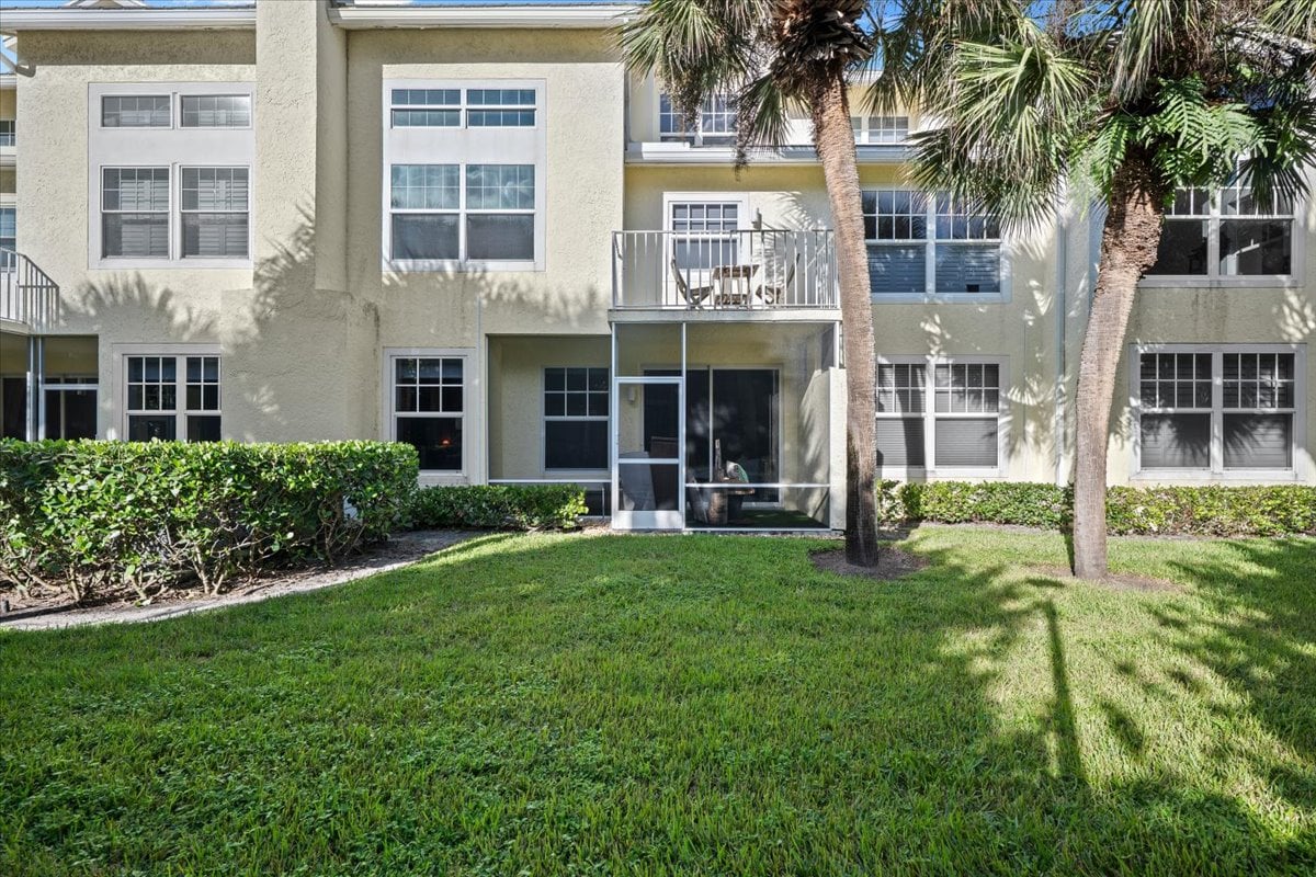Sea Colony condominium exterior with a screened patio, balcony, palm trees, and lawn.