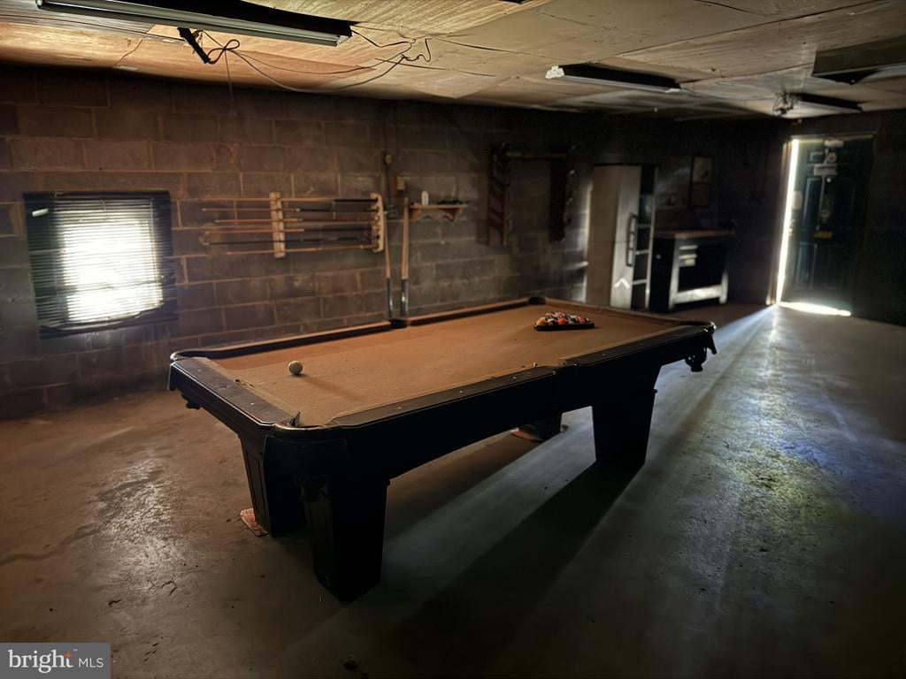 Basement recreation room with a pool table and exposed block walls.