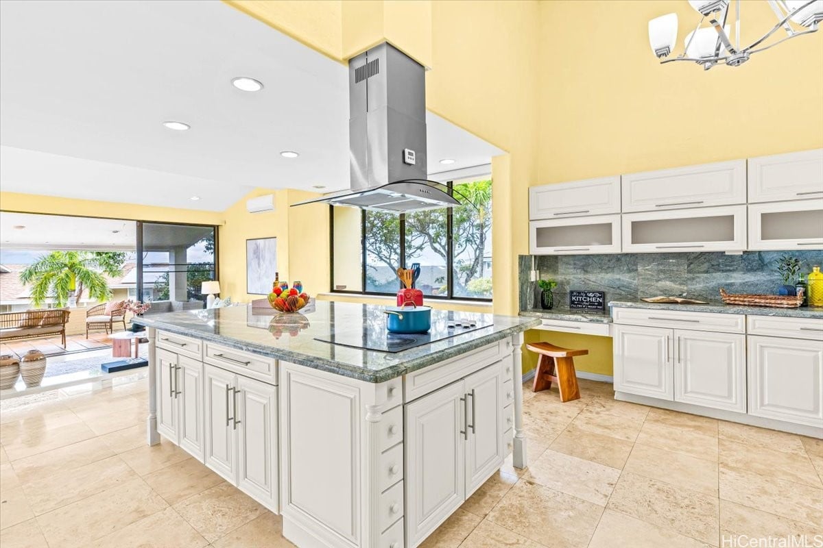 Bright kitchen with a large stone island, white cabinetry, and sliding doors to a covered patio.