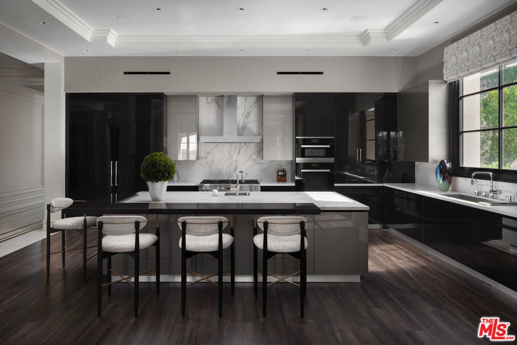 Modern kitchen with glossy black cabinets, marble backsplash, and a large island with three stools.