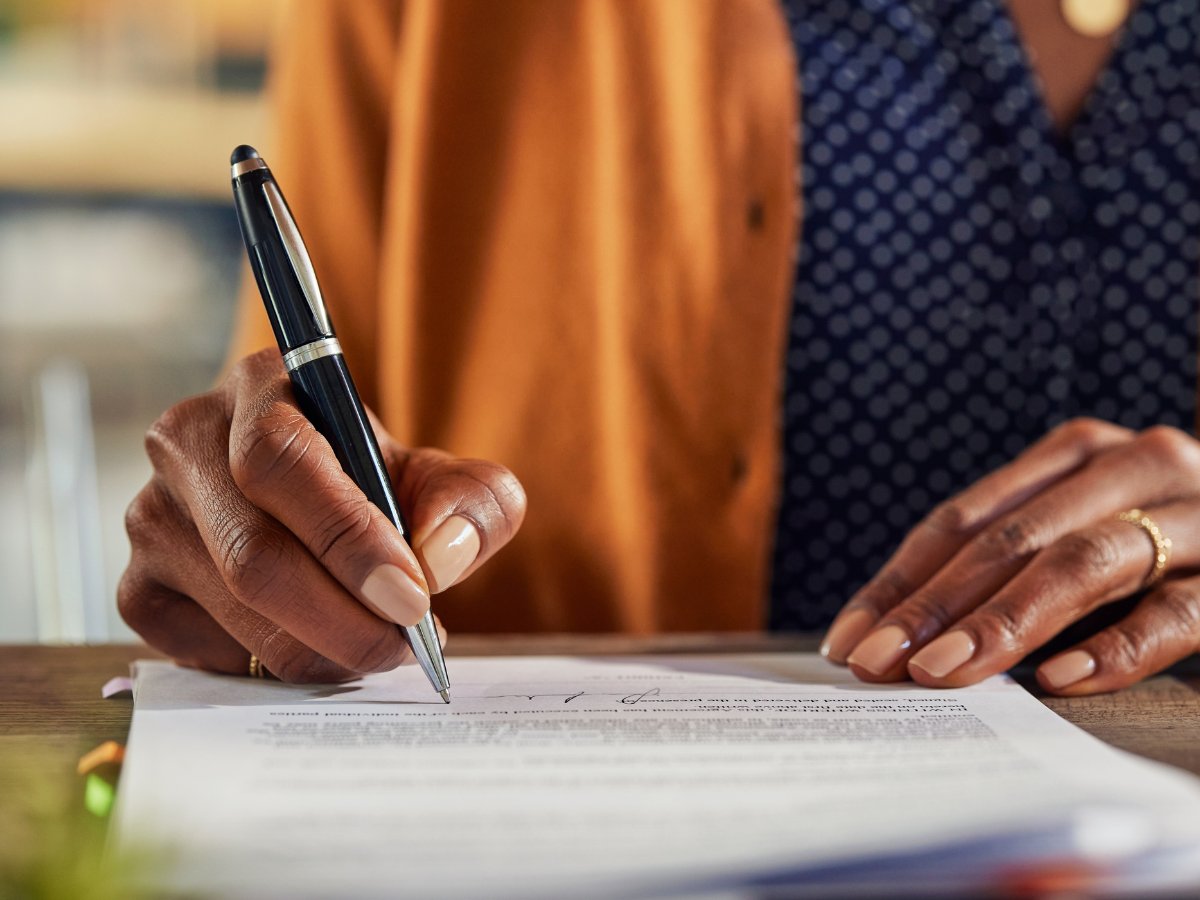 Corpus Christi homeowner signing real estate paperwork during a meeting with a Realtor.