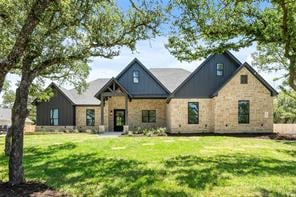 Single-story stone home with dark gables, set behind a broad lawn and mature trees.