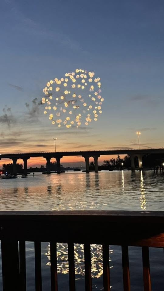Fireworks bursting over the Indian River Lagoon and the Barber Bridge in Vero Beach at dusk