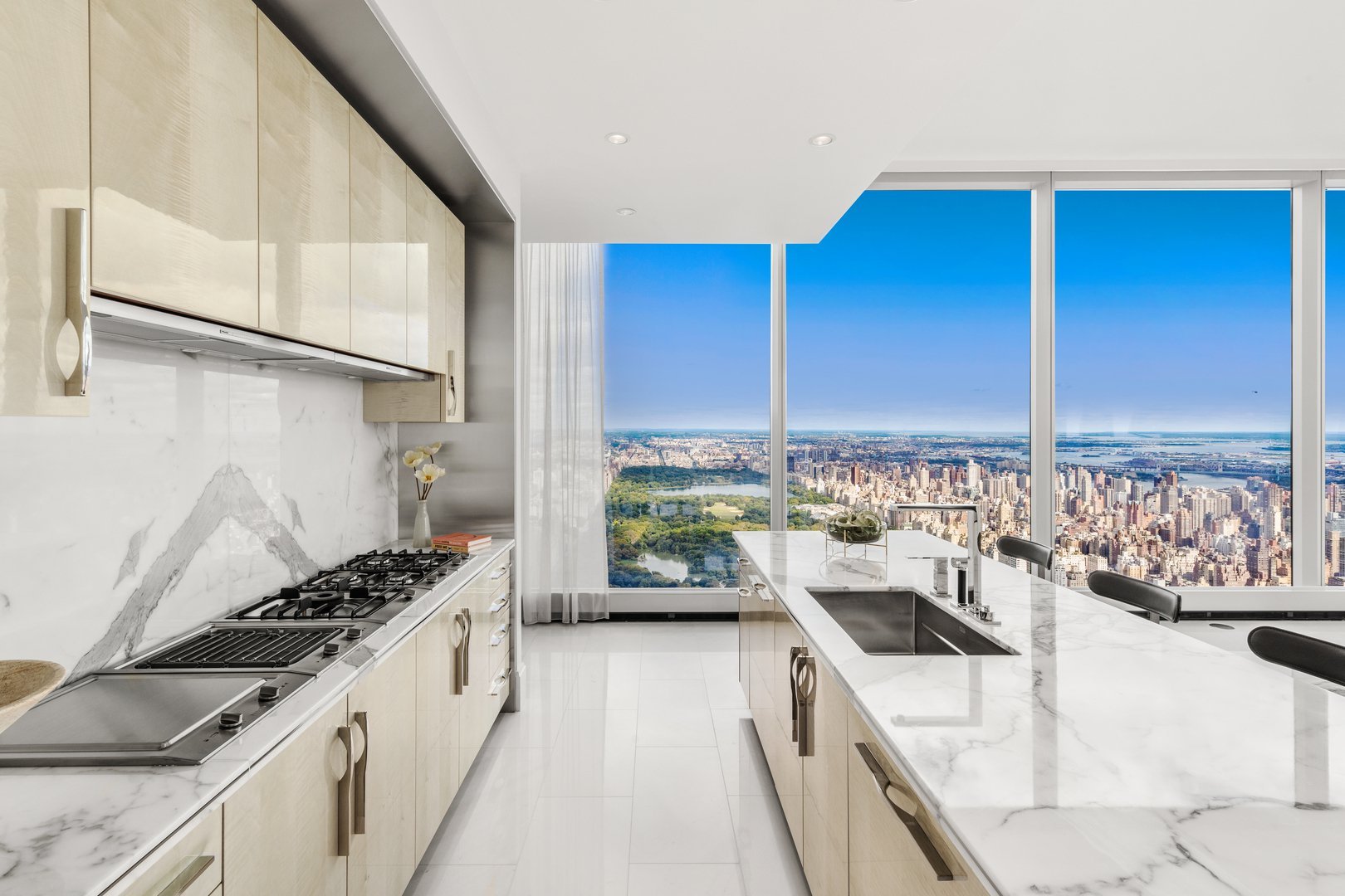 Modern marble kitchen with floor-to-ceiling windows overlooking Central Park and the Manhattan skyline.