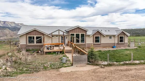 Single-story ranch home with a raised wooden porch and ramp, with mountains in the background.