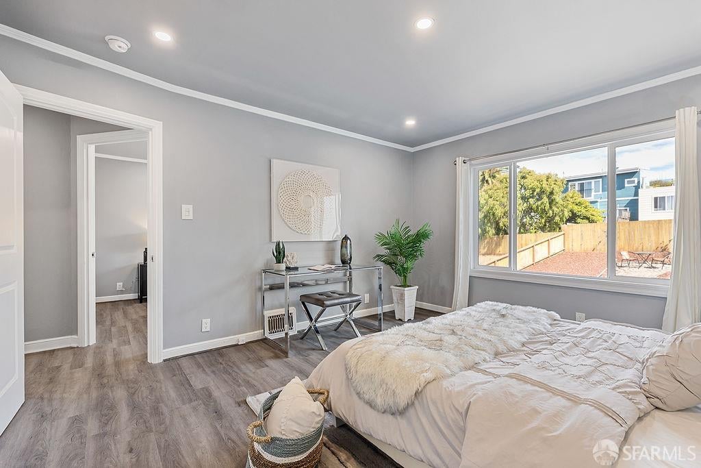 Staged bedroom with a large bed, console desk, and wide window overlooking a fenced yard.